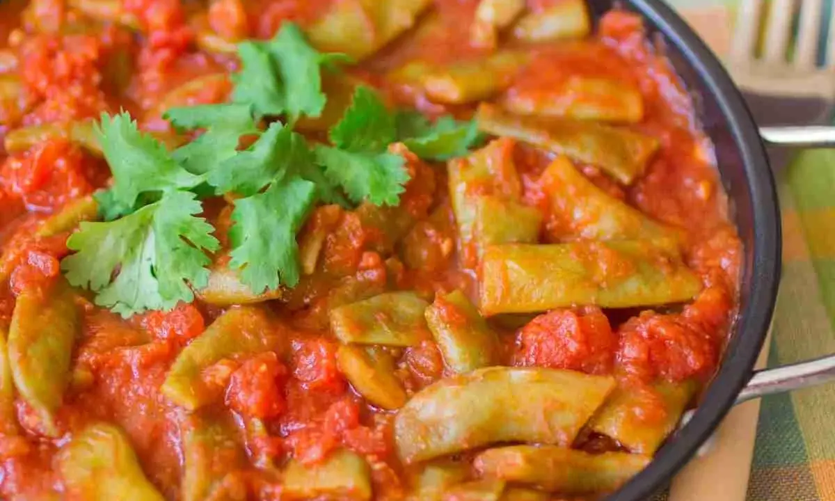 Taccole al pomodoro cotte in padella, guarnite con prezzemolo fresco. Un piatto semplice e gustoso.