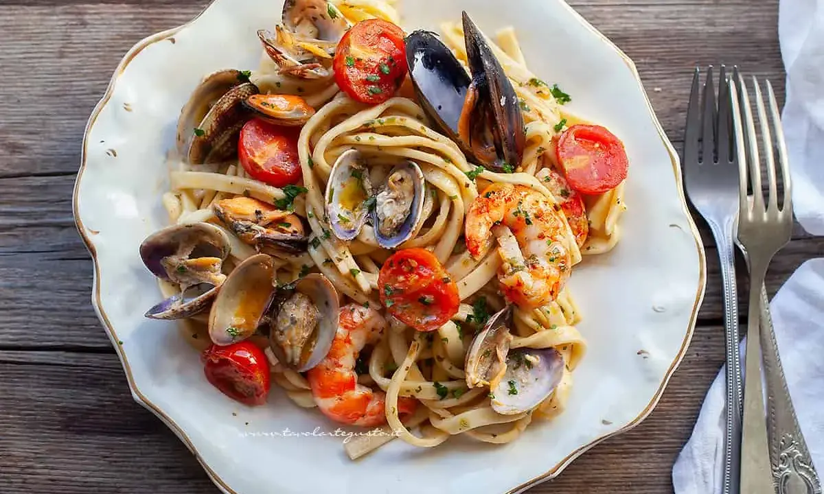 Un piatto invitante di scialatielli ai frutti di mare, con cozze, vongole, gamberi e pomodorini freschi, guarnito con prezzemolo.
