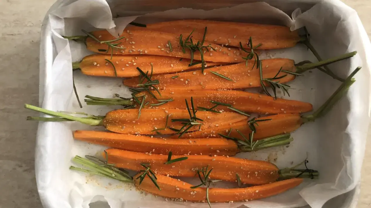 Carote al forno, condite con rosmarino e semi di sesamo, pronte per essere gustate.