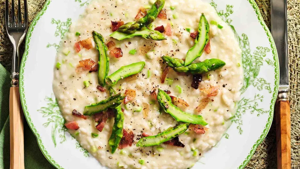 Un cremoso risotto asparagi e zafferano, guarnito con punte di asparagi freschi e cubetti croccanti di pancetta.