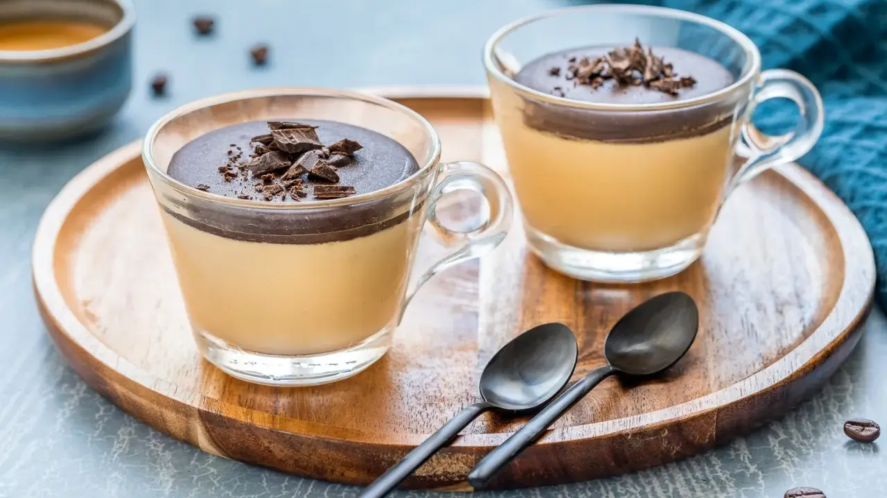 Delizioso semifreddo al caffè con copertura al cioccolato e scaglie croccanti, servito in coppette di vetro su un vassoio di legno.