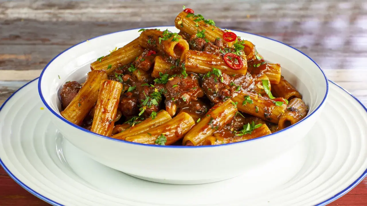 Rigatoni conditi con un ricco ragù di polpo, guarniti con prezzemolo fresco e peperoncino.