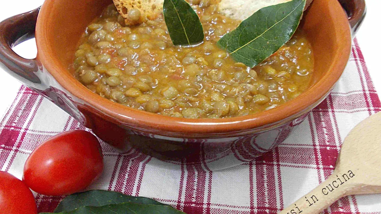Un piatto fumante di lenticchie in umido, guarnito con crostini e foglie di alloro, pronto per essere gustato.