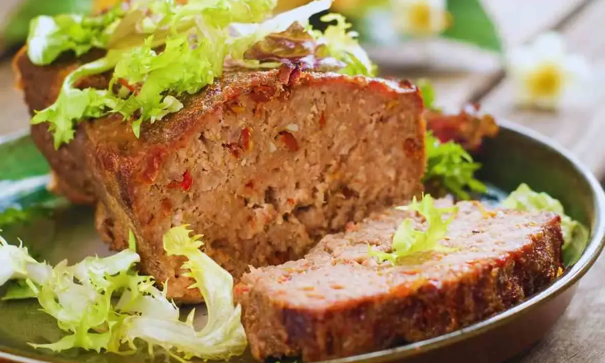 Un succulento polpettone al forno, tagliato a fette e guarnito con insalata fresca.