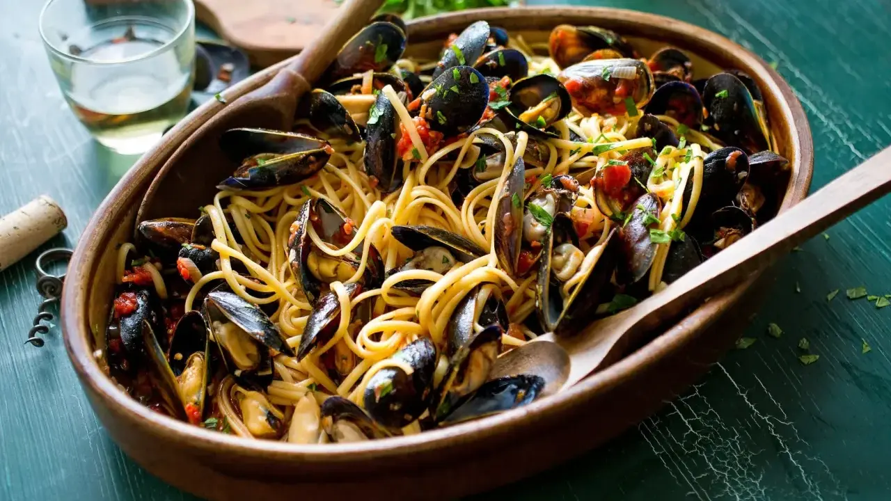 Un invitante piatto di spaghetti con le cozze, condito con pomodoro e prezzemolo, pronto per essere gustato.
