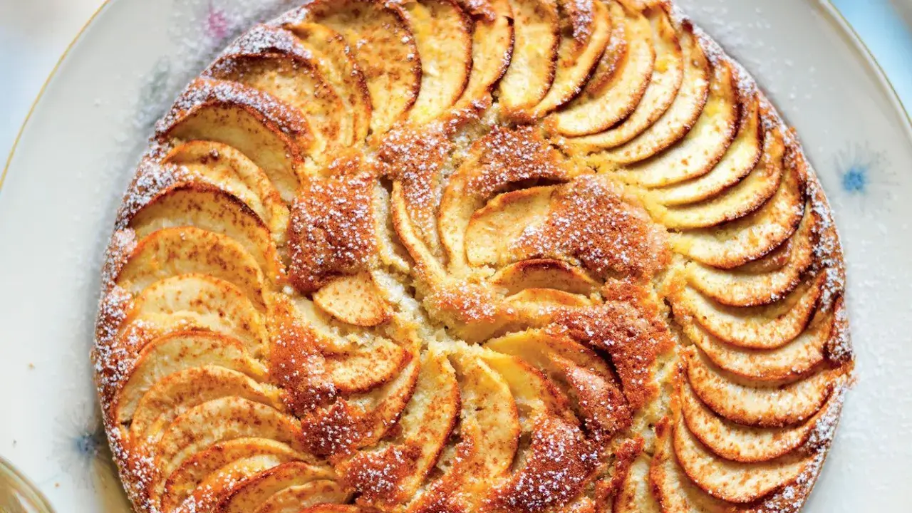 Una deliziosa torta di mele, con fette disposte a raggiera e una spolverata di zucchero a velo.