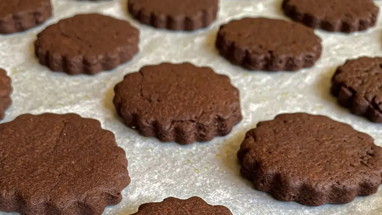 Deliziosi biscotti senza burro al cacao, con bordo ondulato, disposti su una teglia.
