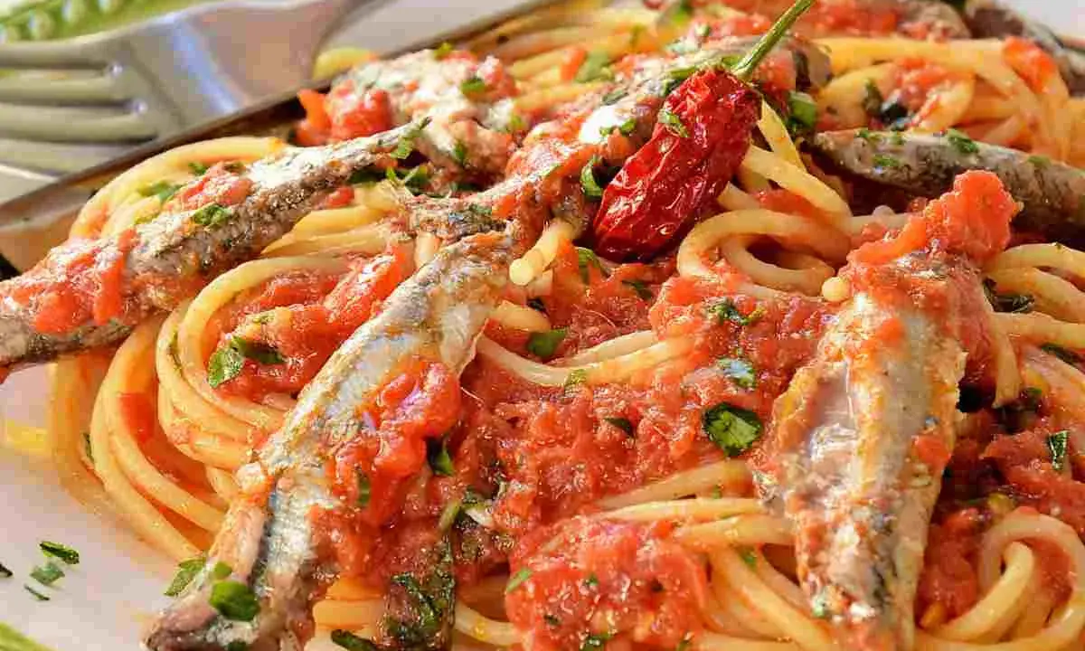 Spaghetti con sugo di pomodoro, acciughe intere e un peperoncino rosso piccante. Un piatto di pasta semplice e saporito.