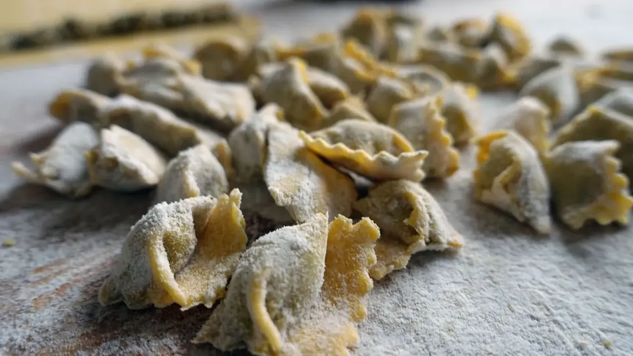 Un mucchio di ravioli del plin freschi, spolverati di farina, pronti per essere cucinati.