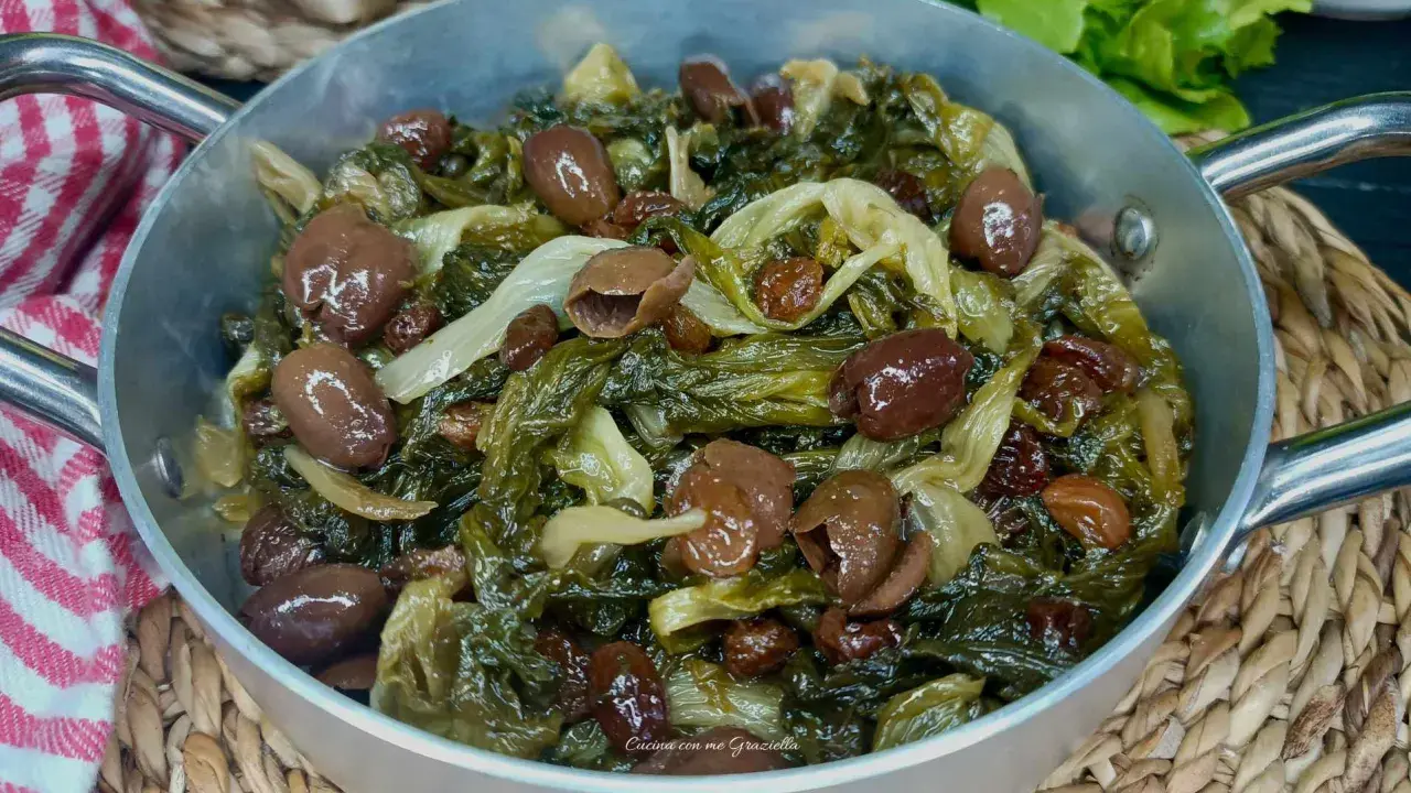 Scarola in padella con olive e uvetta, un contorno saporito e colorato, pronto per essere gustato.