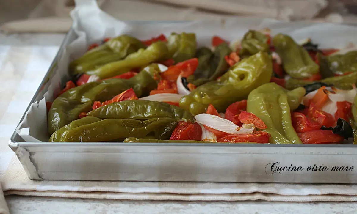 Friggitelli al forno con pomodori e cipolla, un contorno saporito e colorato, pronto per essere gustato.