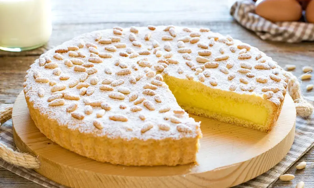 Una deliziosa torta della nonna, con crema gialla, ricoperta di pinoli e zucchero a velo, pronta per essere gustata.
