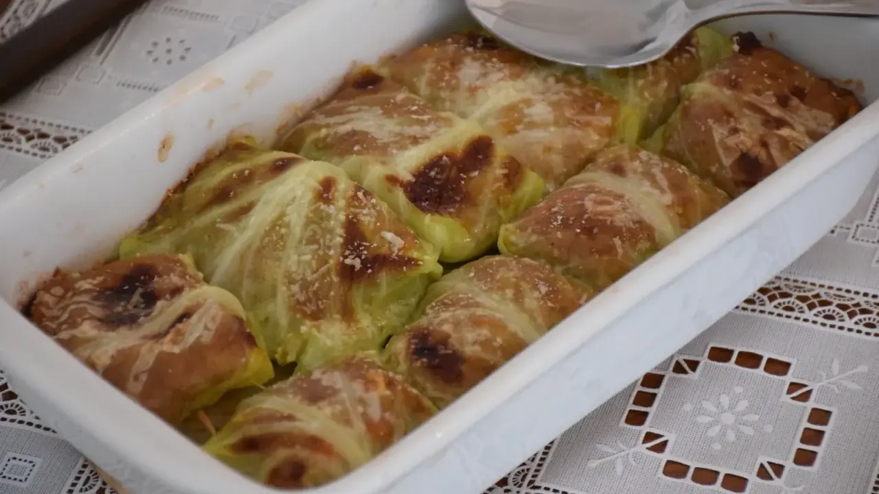 Involtini di verza con carne appena sfornati, dorati e spolverati di parmigiano, pronti per essere gustati.