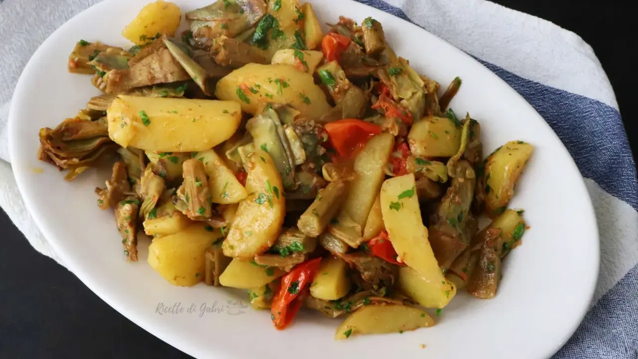 Deliziosi carciofi e patate in padella, un contorno saporito e colorato, arricchito da pomodorini e prezzemolo fresco.