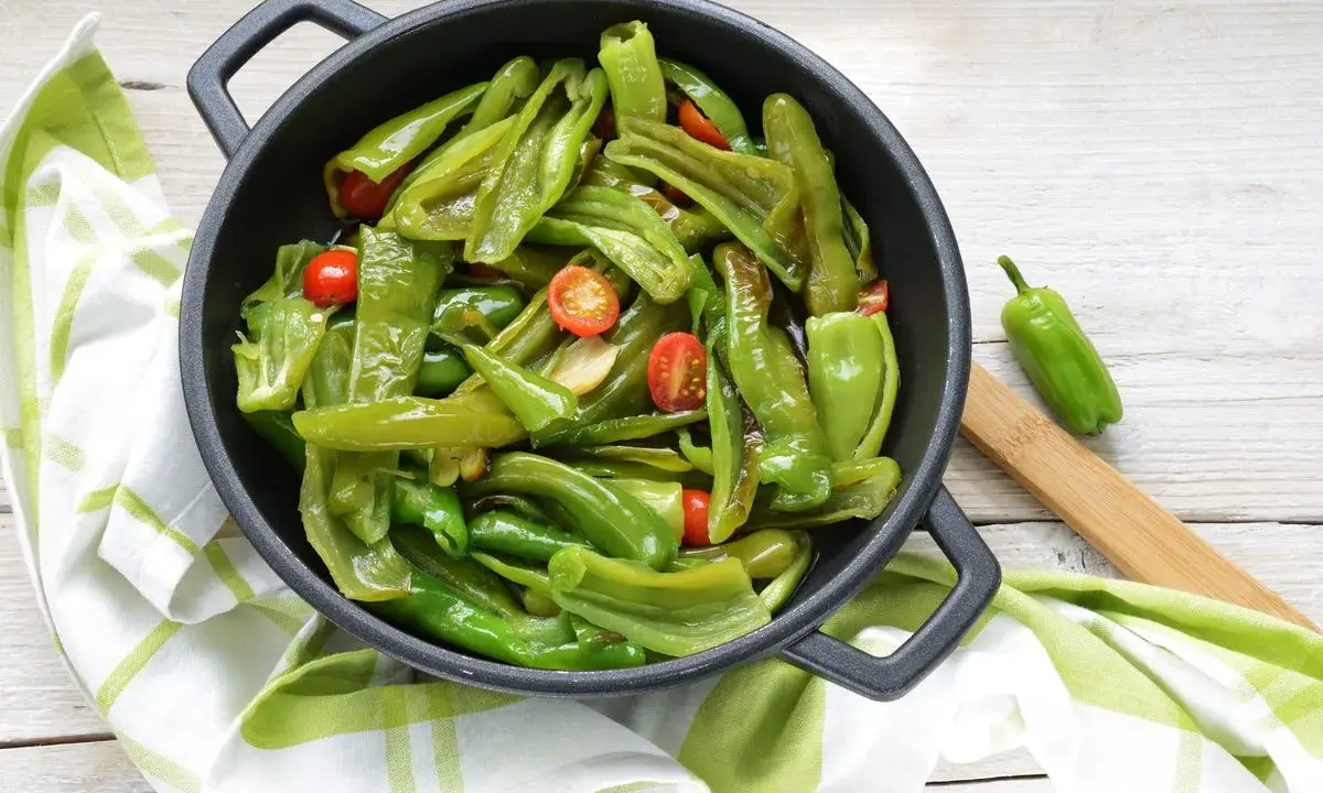 Friggitelli in padella, saltati con pomodorini e aglio, pronti per essere gustati.
