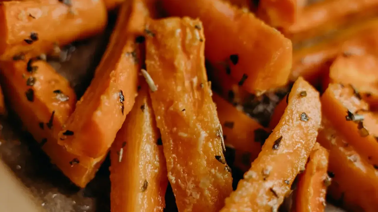 Carote in padella, tagliate a bastoncino e condite con erbe aromatiche, pronte per essere gustate.