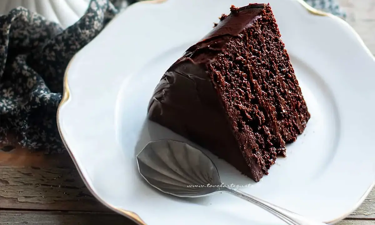 Una fetta di ciambellone al cioccolato, soffice e golosa, su un piatto bianco con un cucchiaino d'argento.