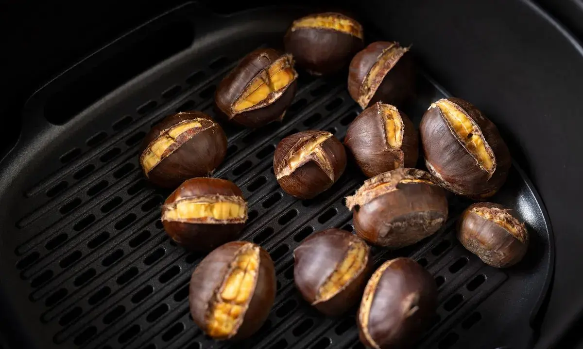 Castagne arrostite nella friggitrice ad aria, con la buccia aperta che rivela il loro interno dorato e invitante.