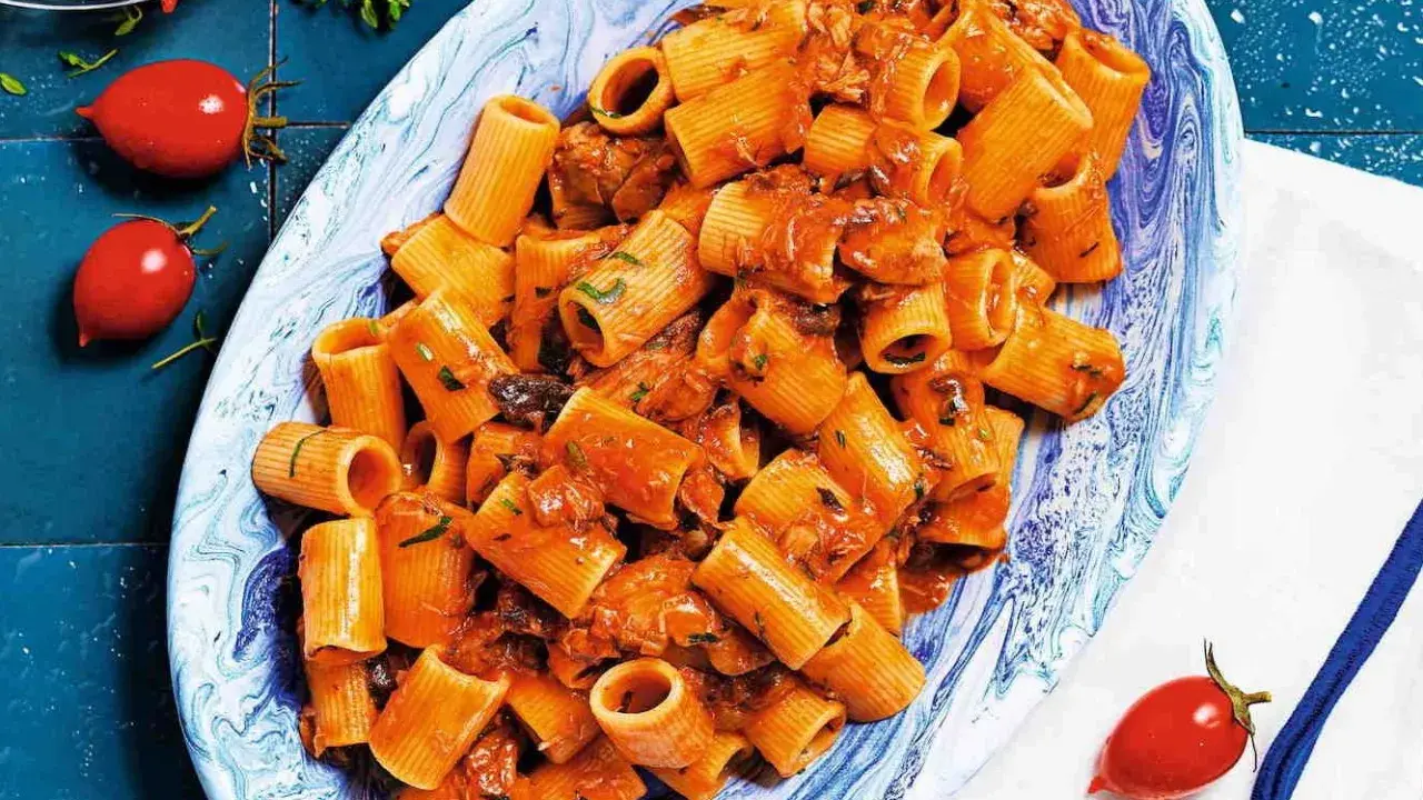 Rigatoni conditi con un sugo rosso saporito, ricco di tonno e erbe aromatiche. Un piatto di pasta al tonno invitante.