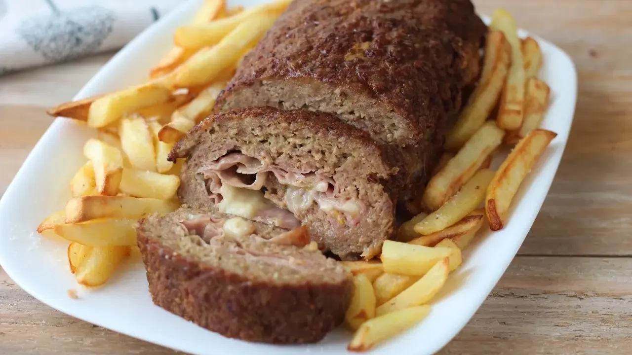 Polpettone ripieno di prosciutto e formaggio, cotto in friggitrice ad aria, servito con patatine fritte croccanti.
