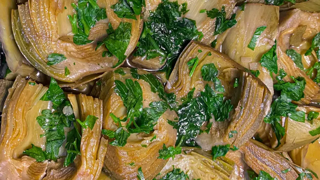 Deliziosi carciofi in padella, teneri e profumati, guarniti con prezzemolo fresco. Un piatto semplice e gustoso.
