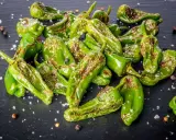 Friggitelli verdi, cotti in friggitrice ad aria, cosparsi di sale grosso e pepe nero su una superficie scura.