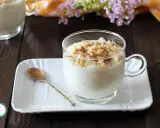 Una tazza di cremosa crema di riso, guarnita con mandorle tritate e cannella, pronta per essere gustata.
