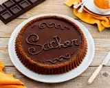 Una crostata morbida al cioccolato, decorata con la scritta "Sacher" in glassa, pronta per essere gustata.