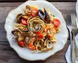 Un piatto invitante di scialatielli ai frutti di mare, con cozze, vongole, gamberi e pomodorini freschi, guarnito con prezzemolo.