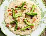 Un cremoso risotto asparagi e zafferano, guarnito con punte di asparagi freschi e cubetti croccanti di pancetta.