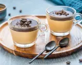 Delizioso semifreddo al caffè con copertura al cioccolato e scaglie croccanti, servito in coppette di vetro su un vassoio di legno.
