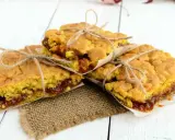 Tre deliziose fette di torta con marmellata, legate con spago e avvolte in carta da forno, pronte per essere gustate.