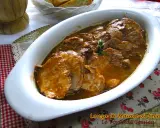 Arrosto di maiale morbido con sughetto, servito in una teglia bianca, pronto per essere gustato.
