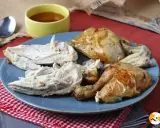 Piatto di petto di pollo arrosto succulento, tagliato a pezzi, con una ciotolina di salsa.