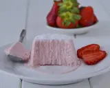 Delizioso semifreddo alle fragole, con una fetta servita su un cucchiaino e guarnito con zucchero a velo e fragole fresche.