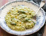 Un cremoso risotto con asparagi, servito in un piatto decorato. Un piatto primaverile che profuma di buono.