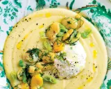 Un cremoso macco di fave fresche, guarnito con ricotta, fave intere, cipollotto e aneto, servito su un piatto decorato.