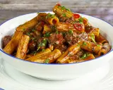 Rigatoni conditi con un ricco ragù di polpo, guarniti con prezzemolo fresco e peperoncino.