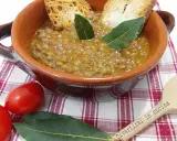 Un piatto fumante di lenticchie in umido, guarnito con crostini e foglie di alloro, pronto per essere gustato.