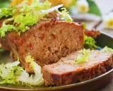 Un succulento polpettone al forno, tagliato a fette e guarnito con insalata fresca.