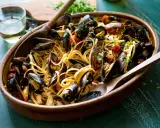 Un invitante piatto di spaghetti con le cozze, condito con pomodoro e prezzemolo, pronto per essere gustato.