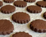 Deliziosi biscotti senza burro al cacao, con bordo ondulato, disposti su una teglia.