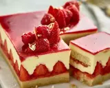 Una fetta di torta alle fragole, con strati di pan di spagna, crema e fragole fresche, guarnita con frutti rossi e foglia d'oro.