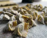 Un mucchio di ravioli del plin freschi, spolverati di farina, pronti per essere cucinati.