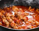 Succulenta carne alla pizzaiola che sobbolle in padella, sprigionando un profumo invitante. Pezzi di carne tenera immersi in un sugo rosso ricco di pomodoro e spezie.