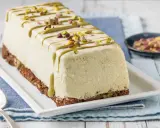 Semifreddo al pistacchio, un dolce gelato decorato con glassa verde e granella di pistacchi, su una base croccante.