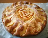 Una deliziosa torta di mele senza glutine, decorata con mele a forma di rosa e spolverata di zucchero a velo.