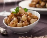 Ciotola di cipolle in agrodolce caramellate, guarnite con menta fresca.