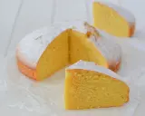 A fluffy lemon cake dusted with powdered sugar, with two slices cut out.