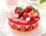 Deliziosa bavarese alle fragole, decorata con fragole fresche, menta e fiorellini bianchi, su una base croccante.